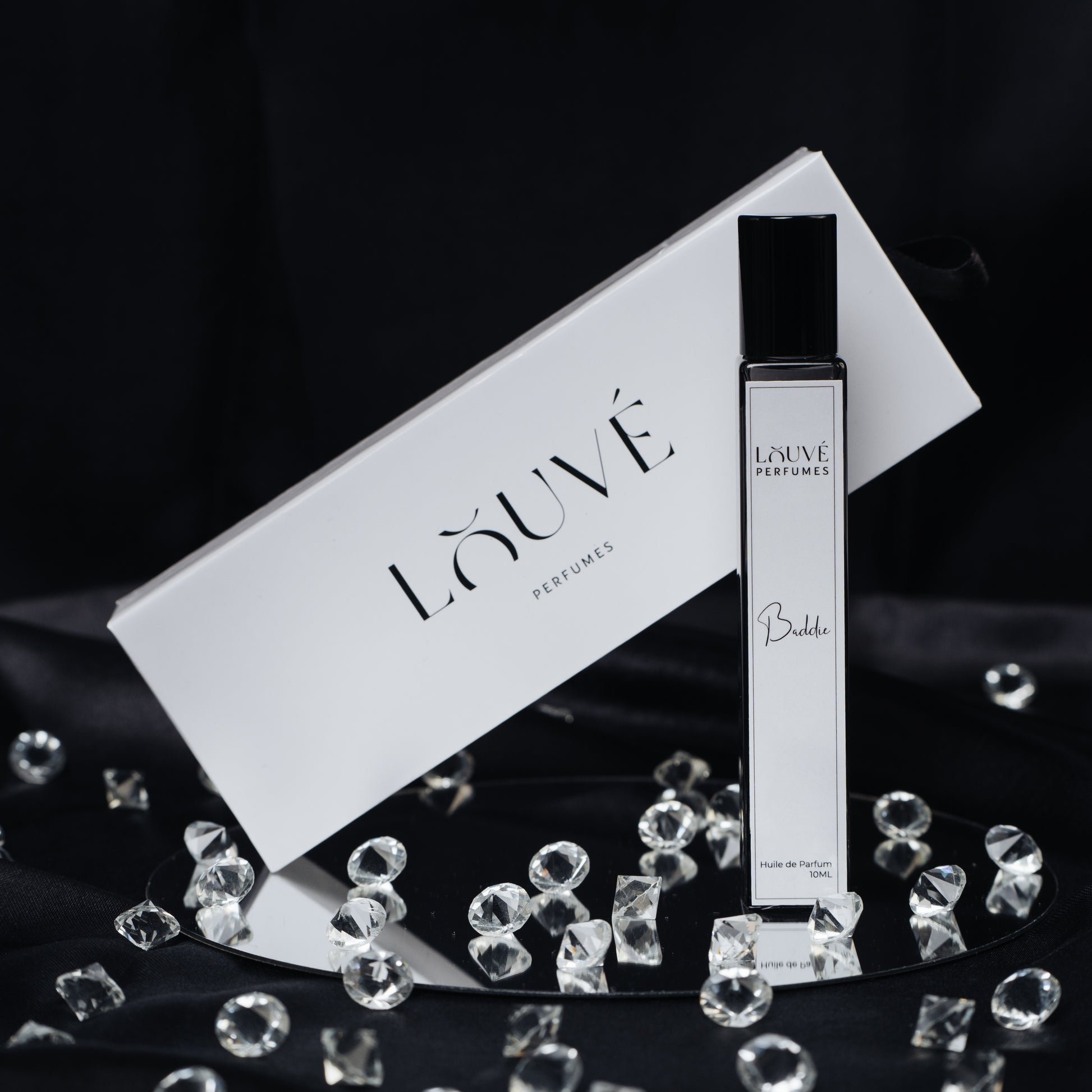 LOUVÉ Baddie Huile Parfumée – eleganter Roll-on Duftflakon mit LOUVÉ Box und Kristall-Dekor auf schwarzem Hintergrund