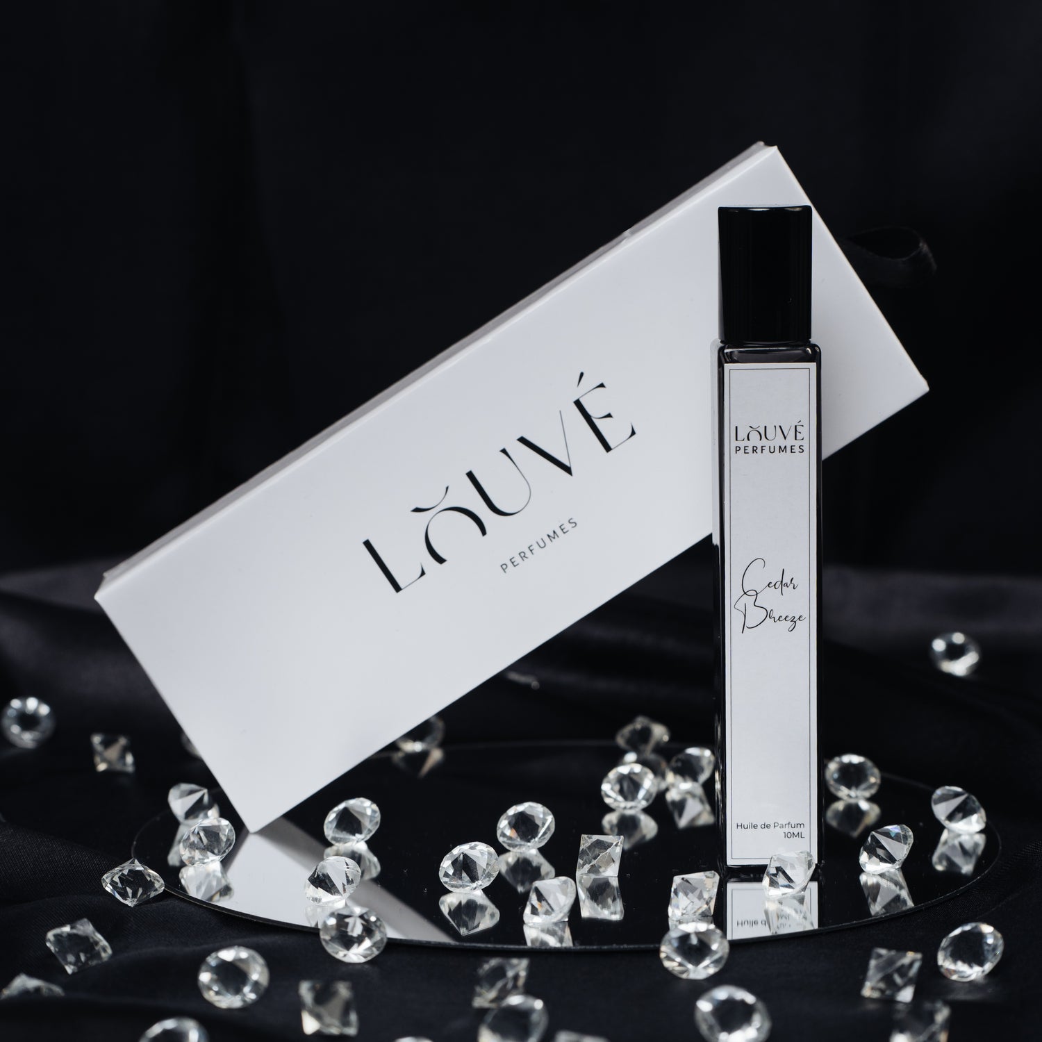 LOUVÉ Cedar Breeze Huile Parfumée – eleganter Roll-on Duftflakon mit LOUVÉ Box und Kristall-Dekor auf schwarzem Hintergrund