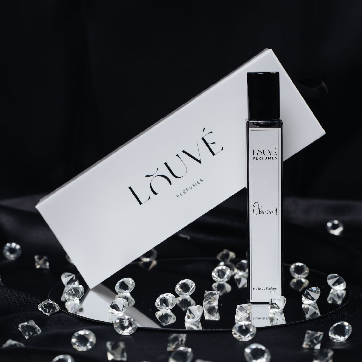 LOUVÉ Obsessed Huile Parfumée – luxuriöse Parfumöl-Flasche mit LOUVÉ Box auf elegantem schwarzen Hintergrund