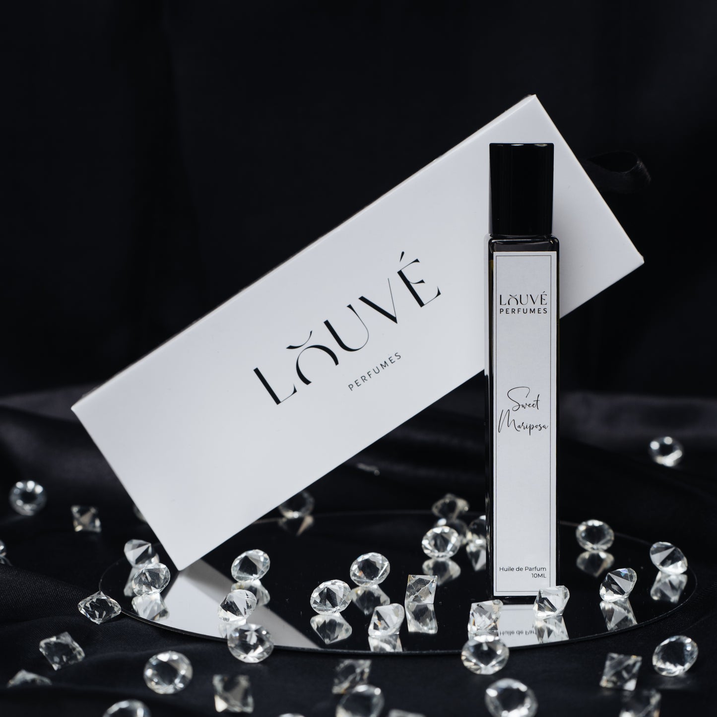 LOUVÉ Sweet Mariposa Huile Parfumée – eleganter Roll-on Duftflakon mit LOUVÉ Box und Kristall-Dekor auf schwarzem Hintergrund